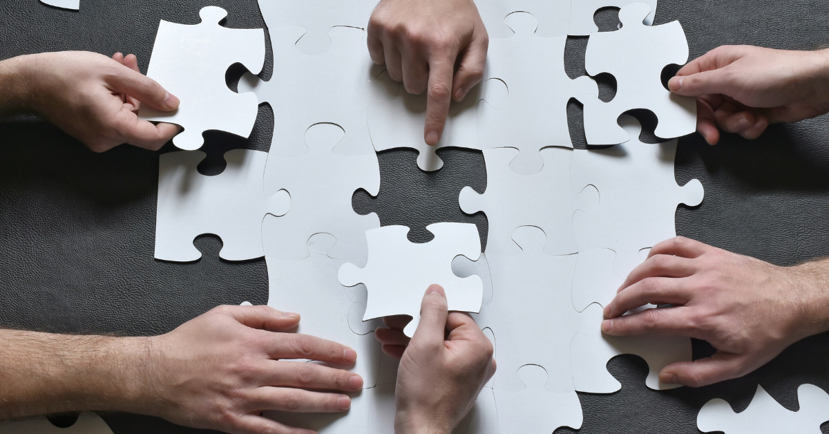 Image of puzzle pieces being assembled by a team